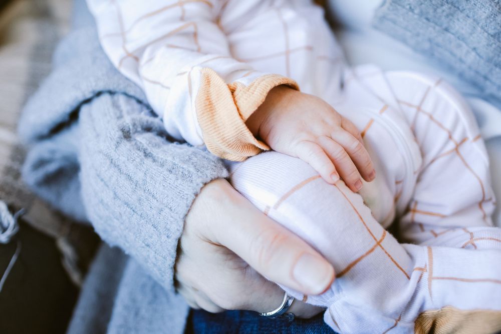 A newborn's hands rests on his lap during newborn photos in Haverhill, MA. Southern Maine newborn photographer.