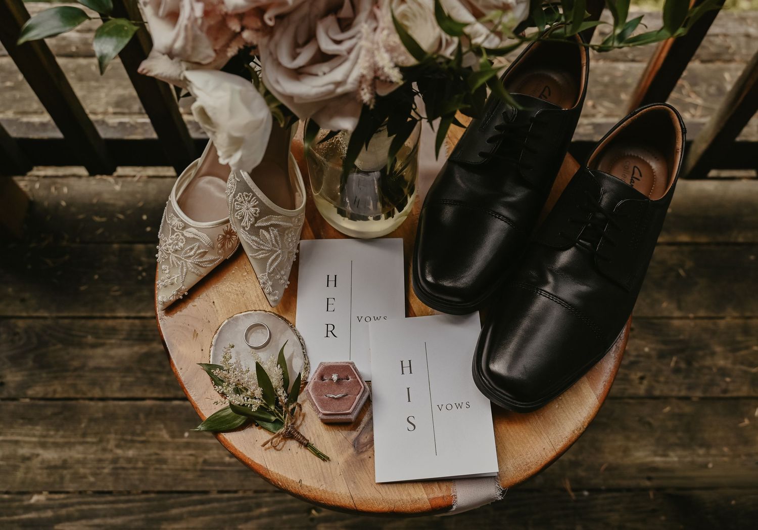 Wedding details including shoes, rings, and floral arrangements artfully displayed on rustic wooden surfaces.