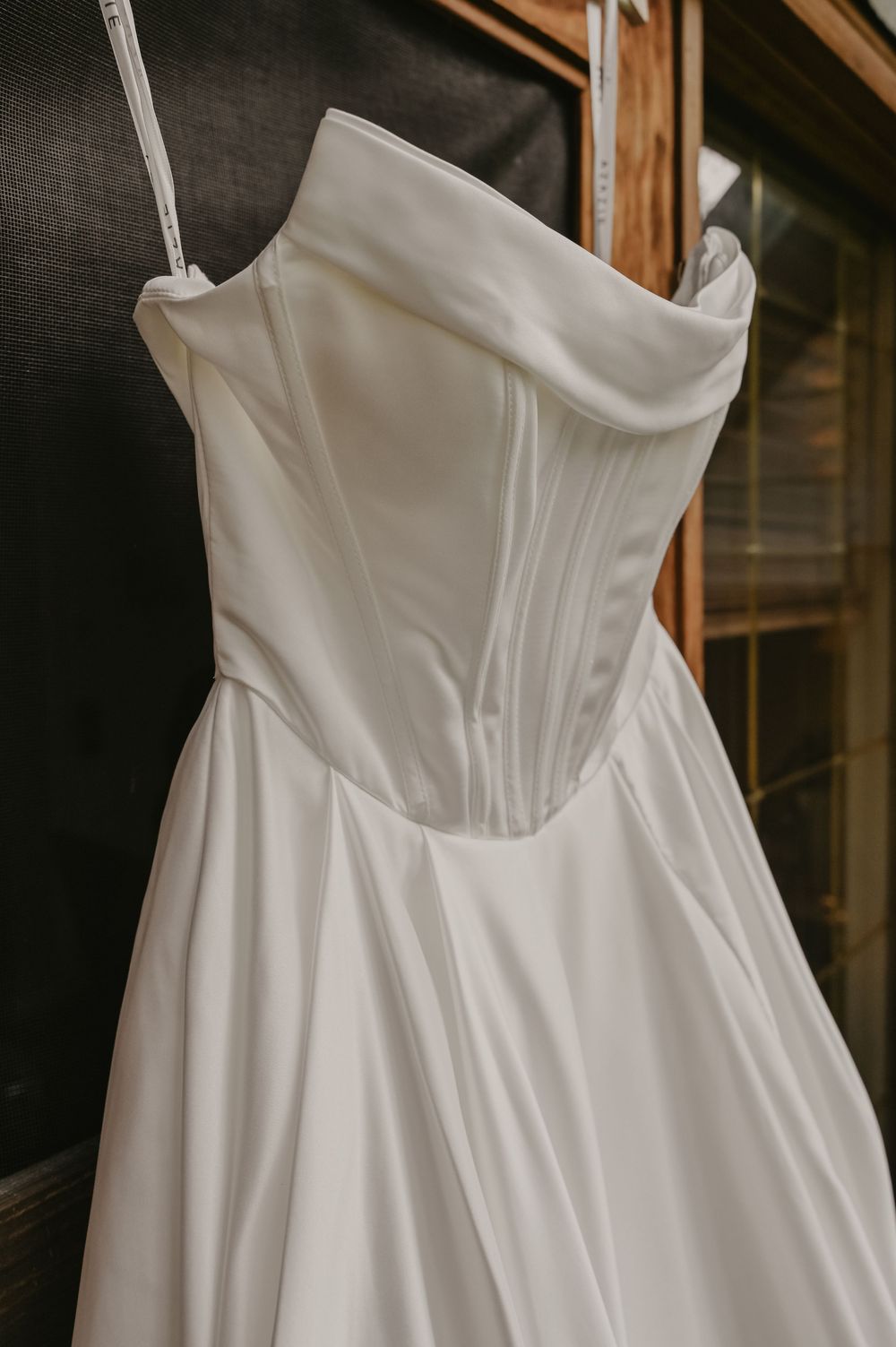 Close-up detail of a white strapless wedding dress bodice with structured corset design hanging on display.