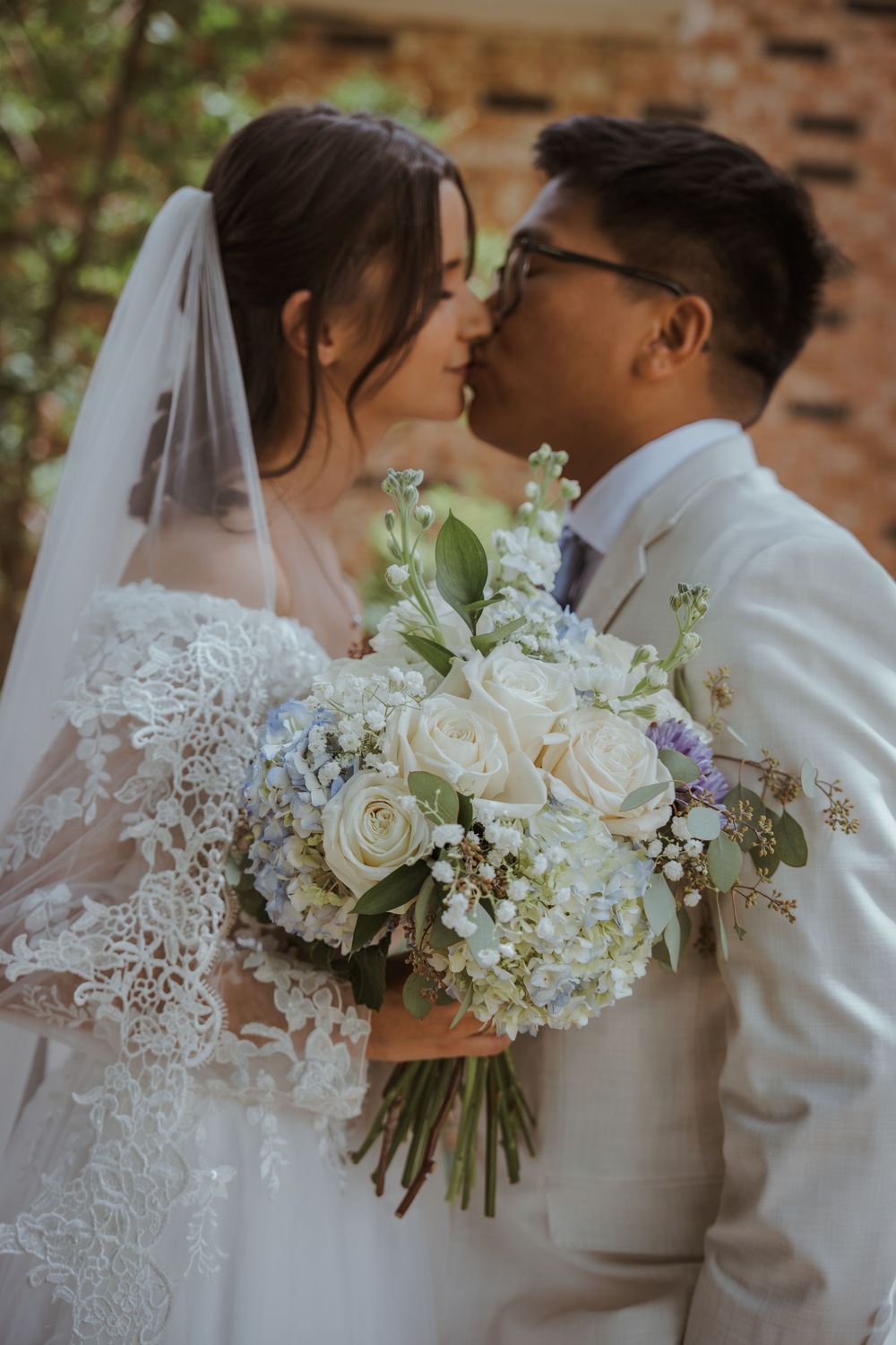 Romantic wedding moment with white bouquet featuring roses and baby's breath.