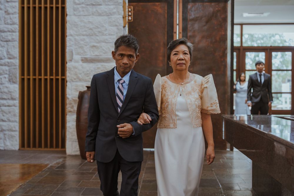 Wedding processional in formal attire walking through a modern church interior.