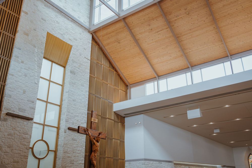 Architectural detail of modern church interior showing wooden ceiling and wall-mounted crucifix.