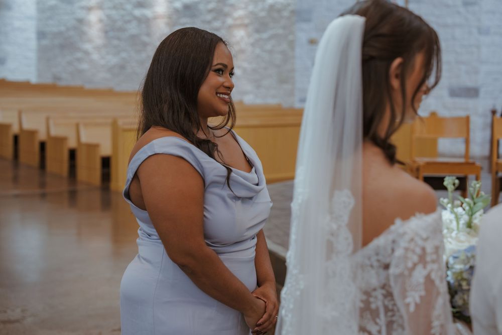 A bridesmaid in a light purple dress shares a joyful moment during a wedding ceremony.