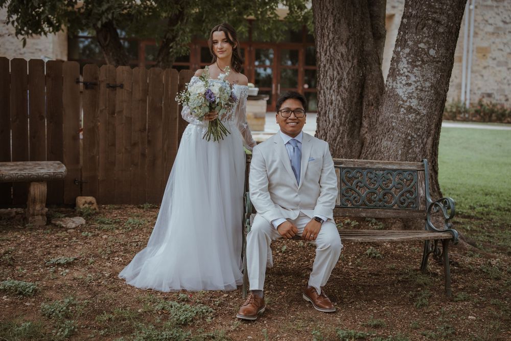 Romantic wedding photos taken under large trees in an outdoor garden setting.