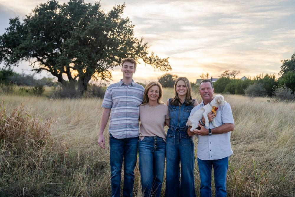 A family group poses in a rustic field setting during sunset.