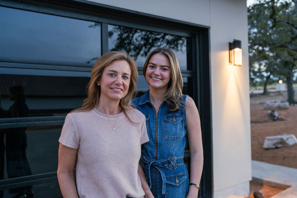 Two people stand together on a modern porch with outdoor lighting.