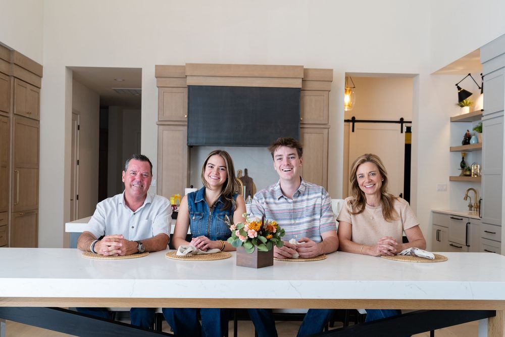 A group sits together at a modern white dining table in a bright kitchen.