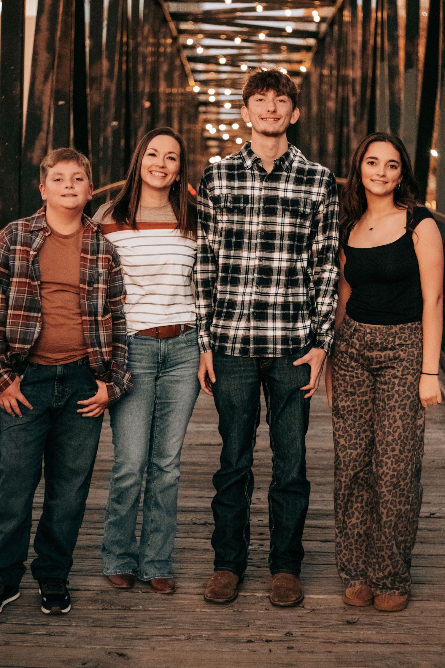 A group of people wearing casual clothing stand together in a rustic wooden setting.