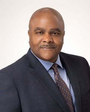 Professional headshot series showing different angles of a person in a dark suit and patterned tie against white background.