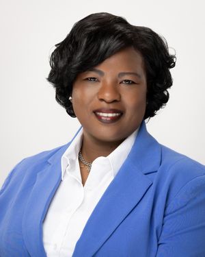 Professional portrait in bright blue blazer and white shirt against light background.