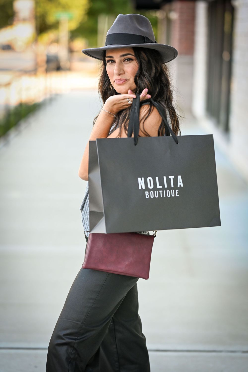 Stylish shopping bags from Nolita Boutique displayed in outdoor setting.