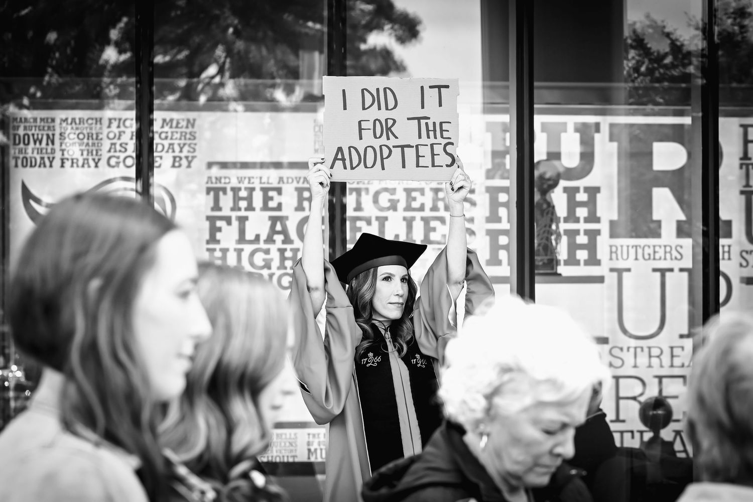 Graduate holding sign at her graduation: I did it for the adoptees.