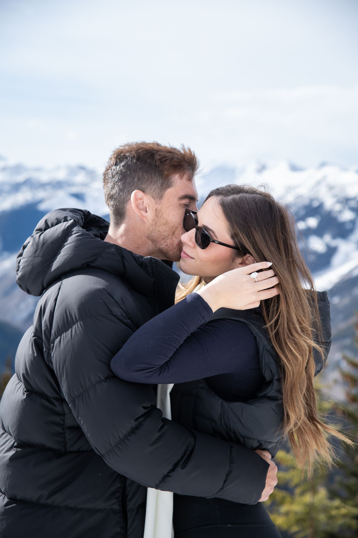 Beautiful engagement photos on top of Aspen mountain at The Aspen Wedding Deck in the winter with snowy mountains in the background.