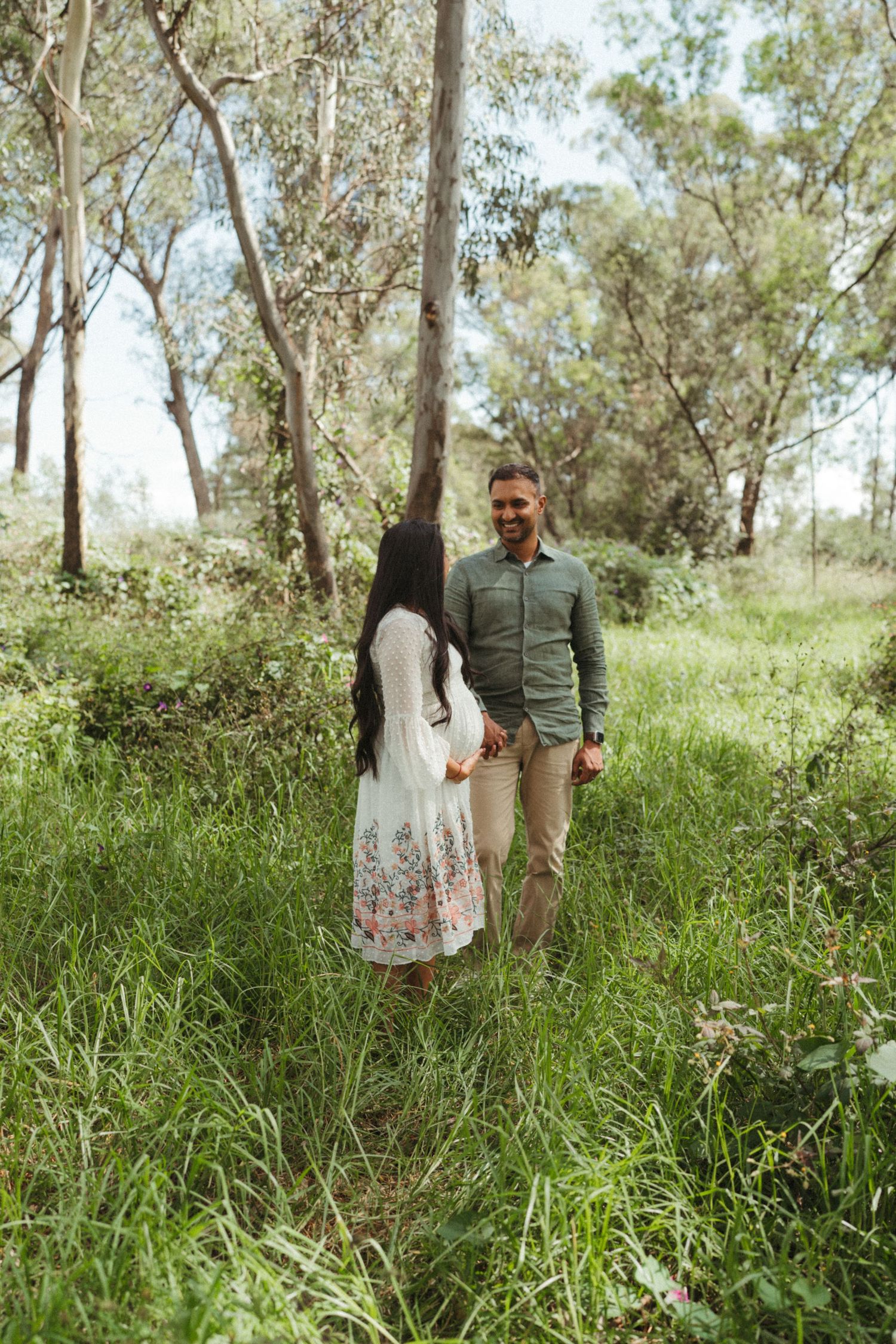 Couple standing together in lush green forest setting.