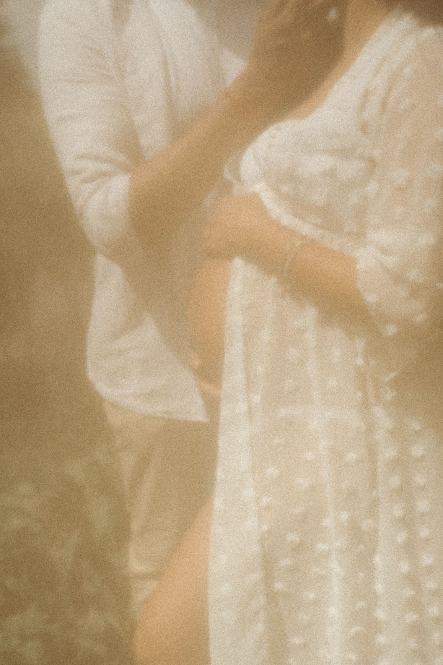 Soft sepia-toned close-up of a lace maternity dress with delicate dot pattern.