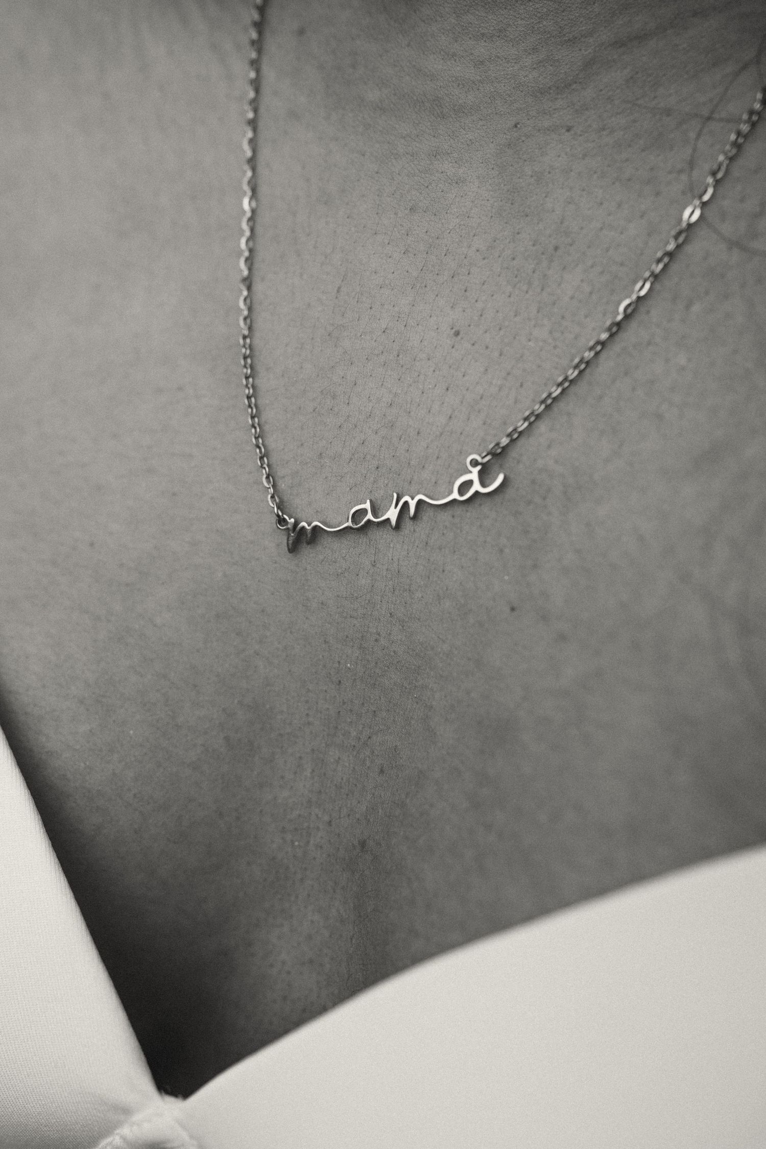 Delicate silver necklace with cursive 'amor' text against grey background.