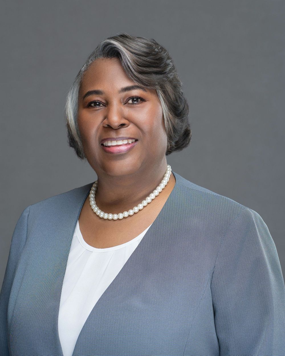 Kelly Photography Atlanta Professional portrait series featuring someone in gray suit with pearl necklace against neutral background.