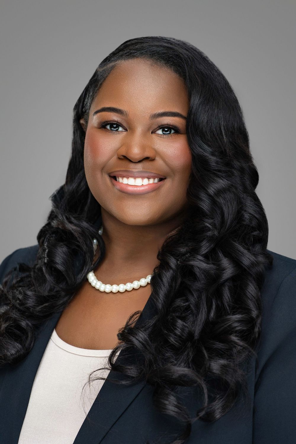 Professional headshot series showing someone in dark blazer with pearl necklace and curled hair. Kelly Photography Atlanta Headshot Session.