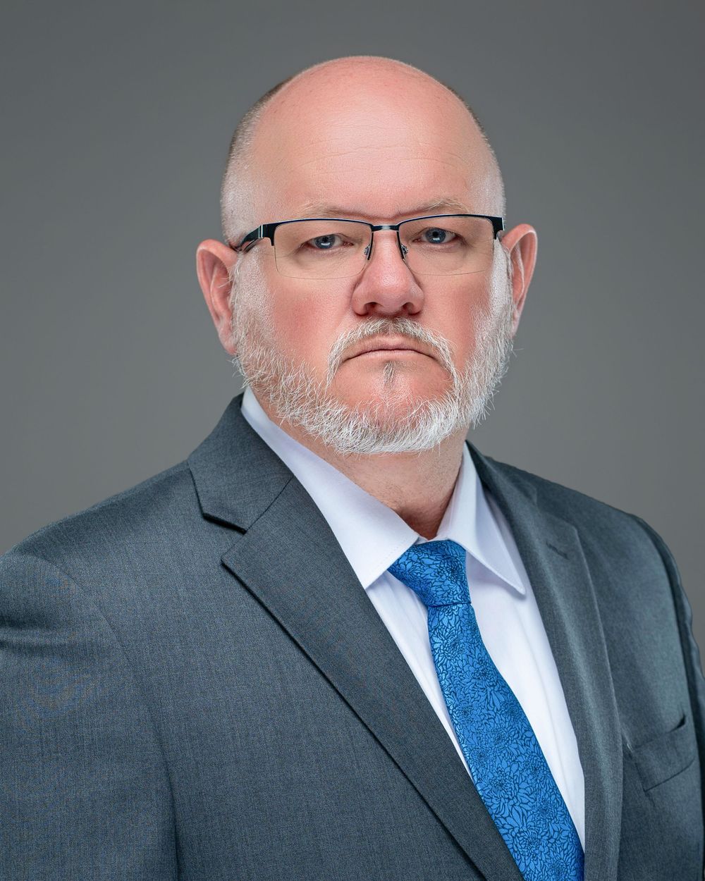 Professional headshot of person in grey suit and blue tie against grey background. Kelly Photography Atlanta Headshot Session. Atlanta GA