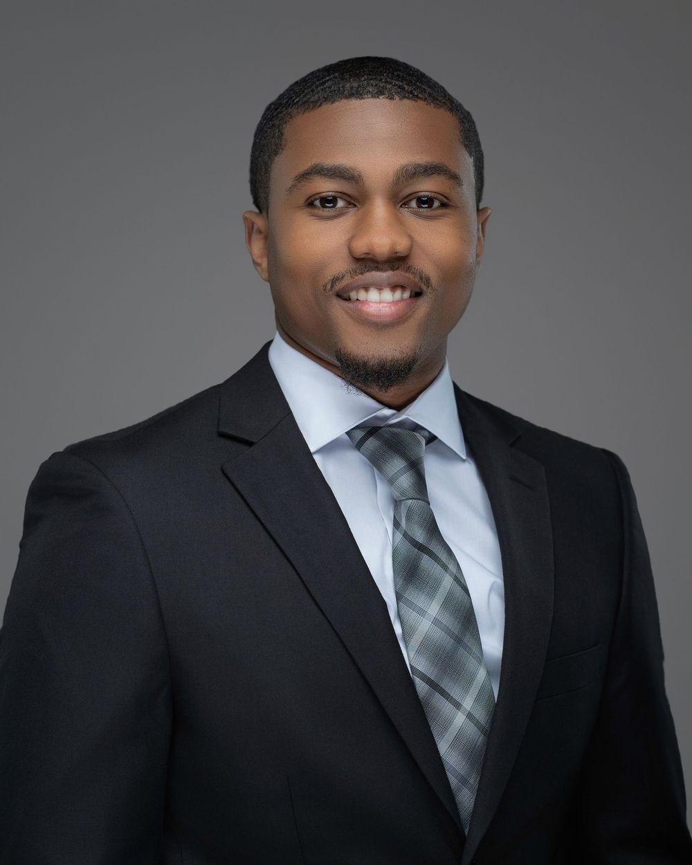Professional portrait of person in dark suit and striped tie against grey backdrop. Kelly Photography Atlanta Headshot Session
