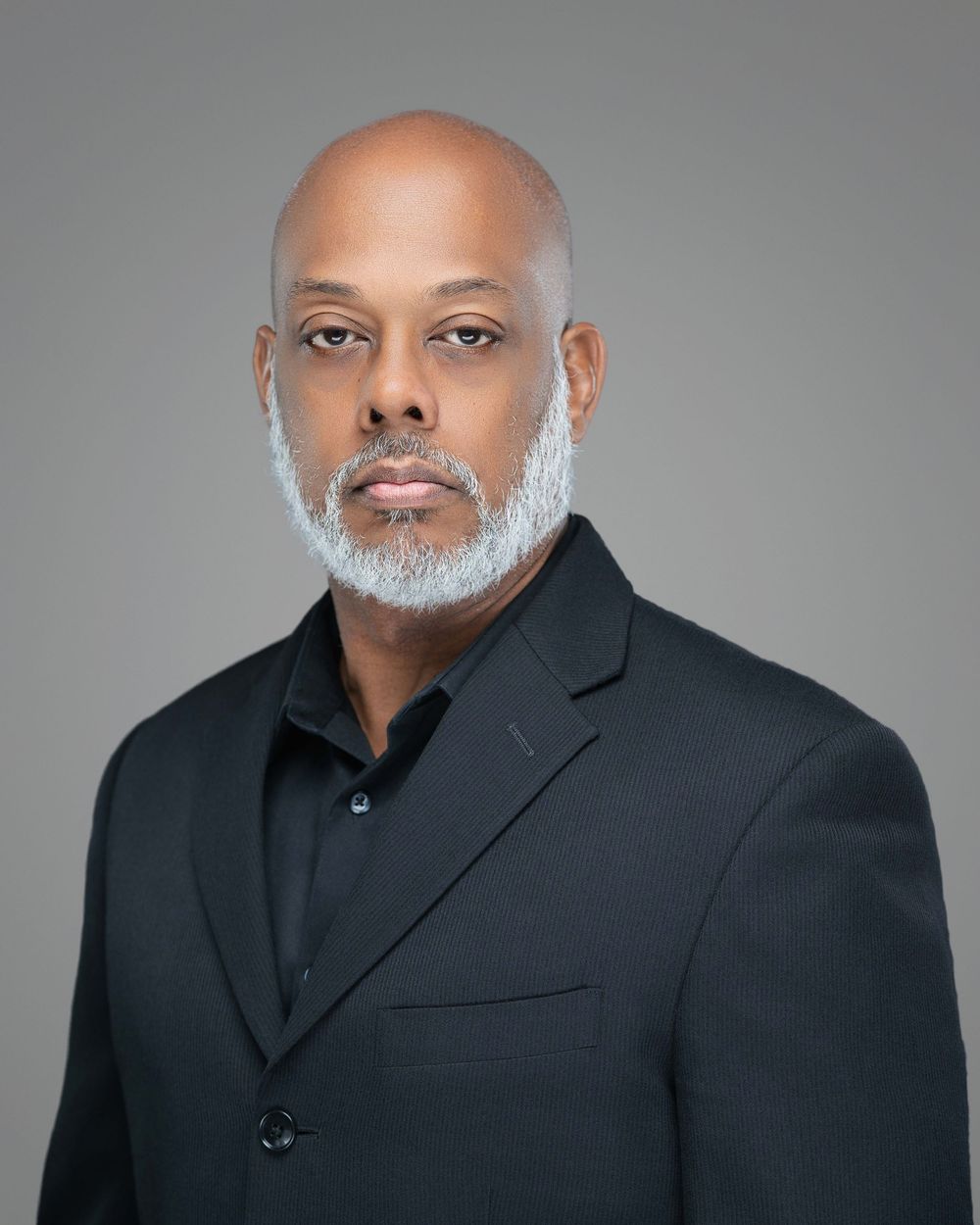 Professional studio portrait series featuring a person in a black suit against a gray background. Kelly Photography Atlanta Headshot Session