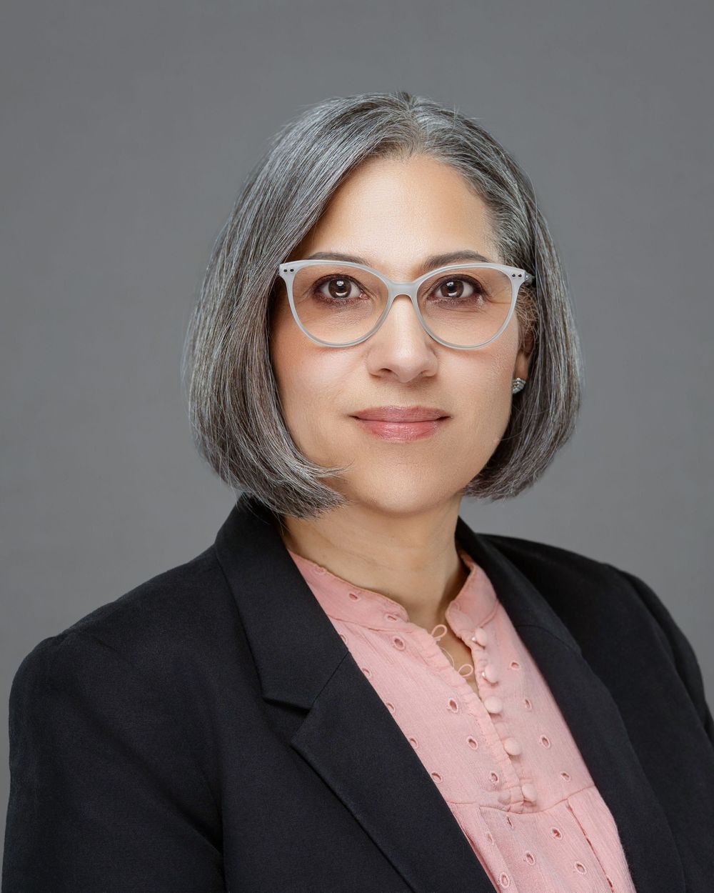 Professional headshot series showing different angles against a gray background wearing a black blazer and pink blouse. Kelly Photography