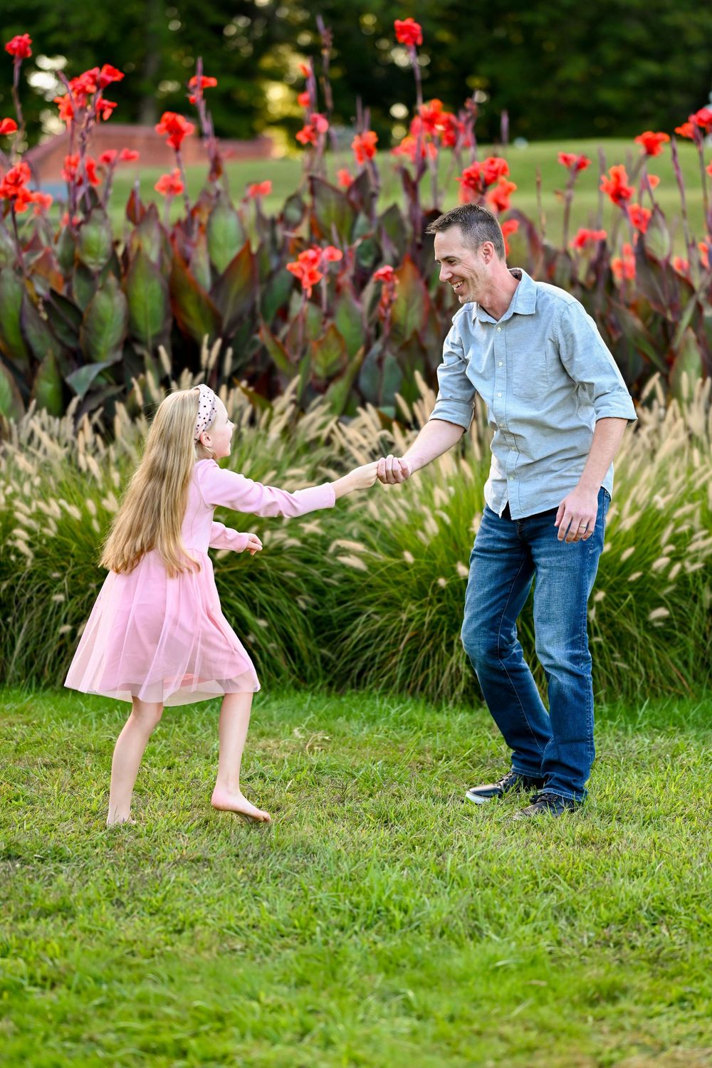 A joyful dance moment in a garden with vibrant red canna lilies blooming in the background.