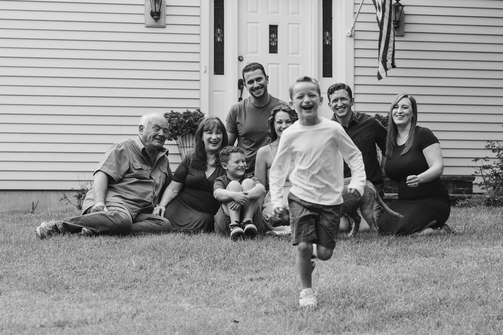 Black and white photo of a multi-generational family gathering outside a white house.