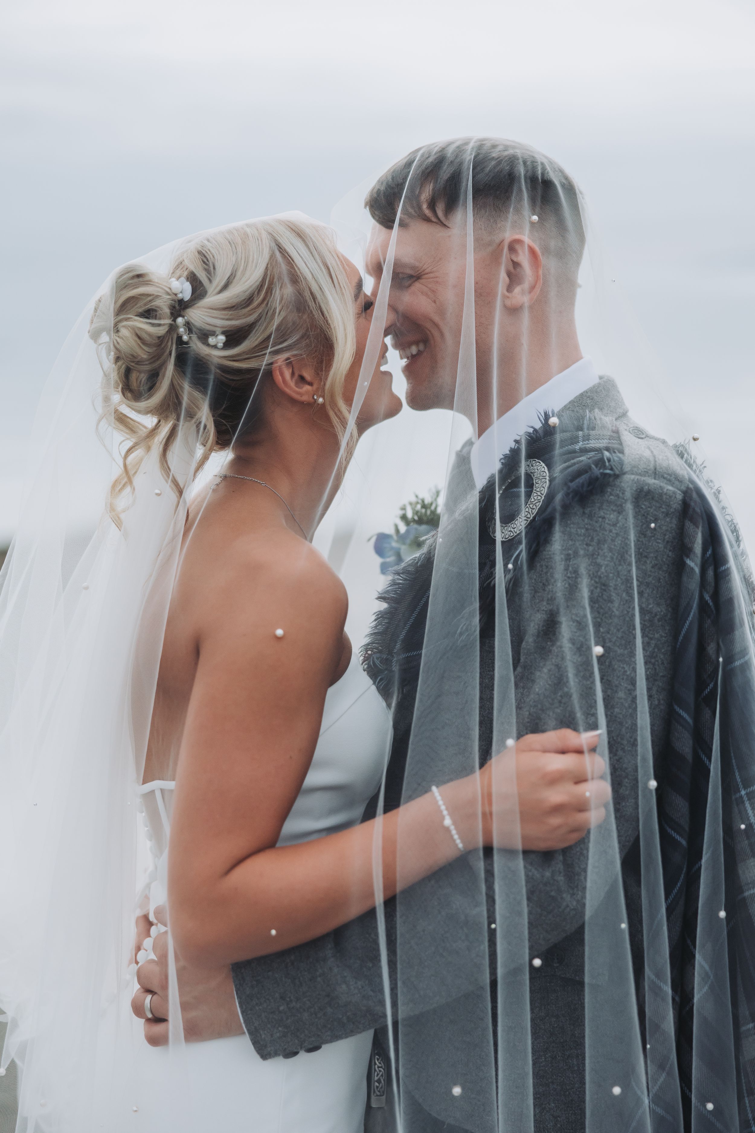 Romantic wedding portraits captured in soft, dreamy lighting with flowing veil details.