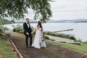 Scenic waterfront wedding photos with rolling hills in background.