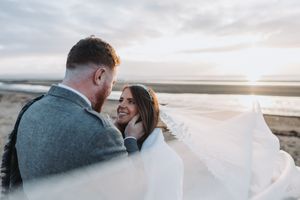 Dramatic sunset wedding portraits with soft lighting and coastal backdrop.