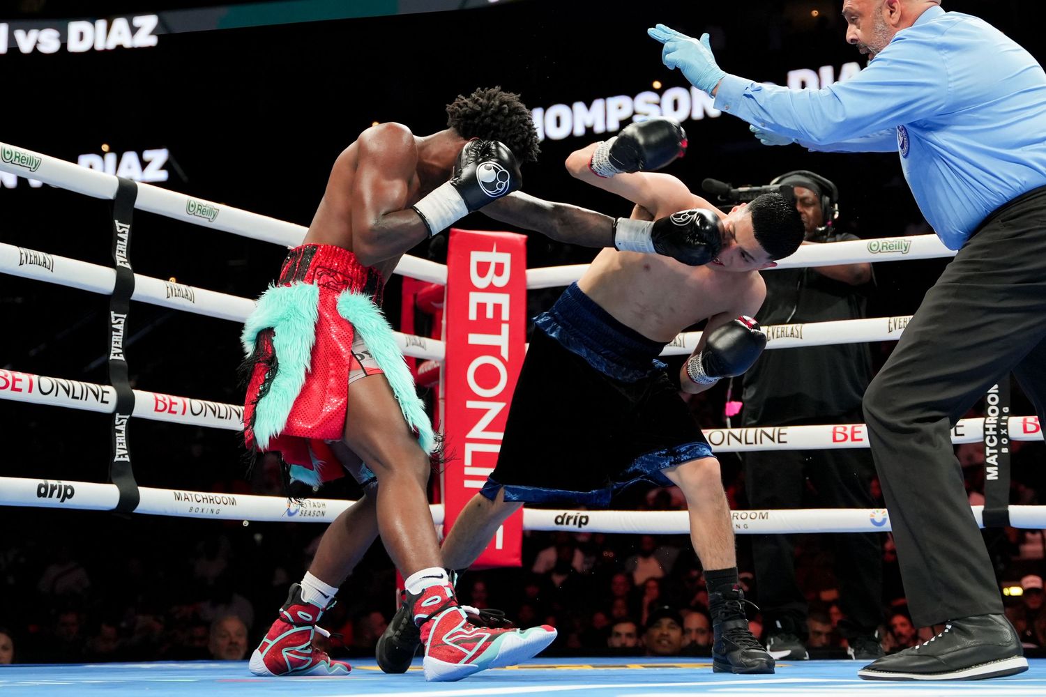 A boxer delivers a powerful punch to his opponent as a referee watches closely in a pro bout.