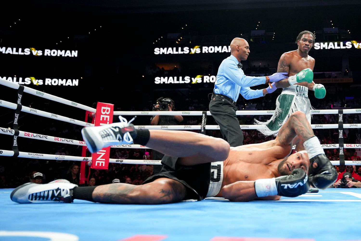 A referee stops the count as a knocked-down boxer lies on the canvas in a Smalls vs Roman fight.