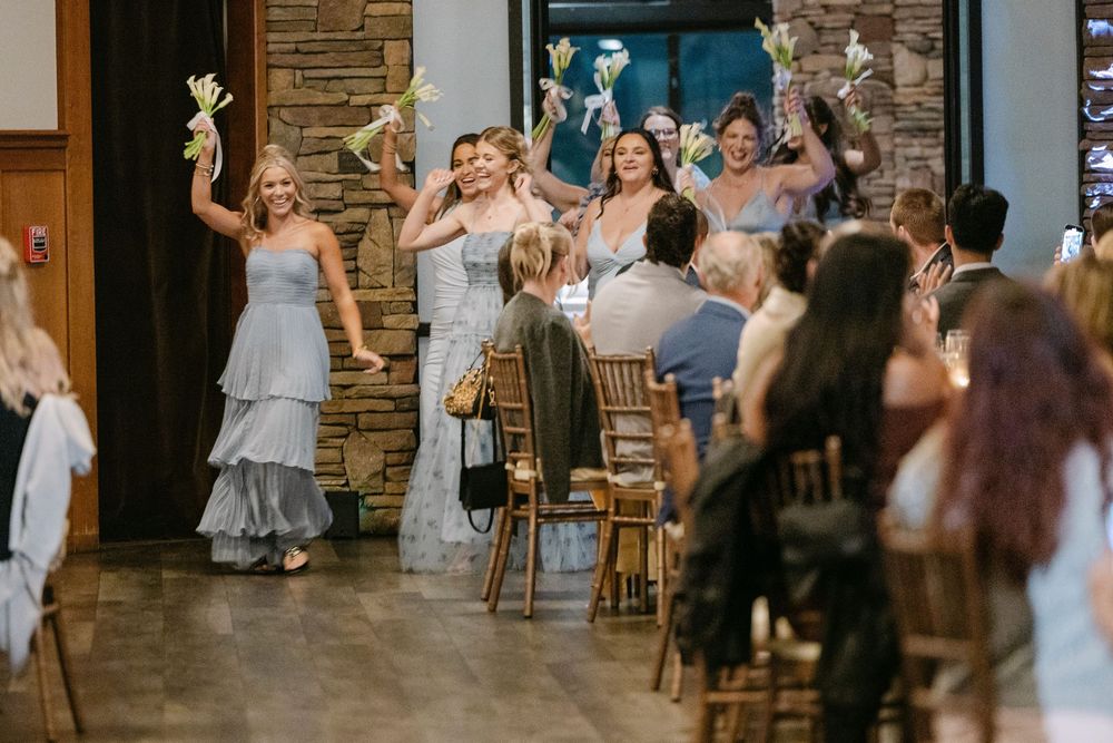 Wedding guests dancing and celebrating together on a rustic dance floor with exposed brick walls.