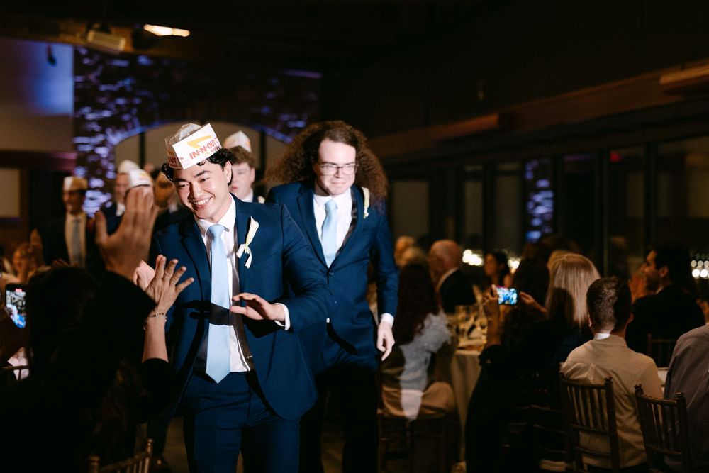 Wedding guests dancing and celebrating on a dimly lit dance floor at an evening reception.