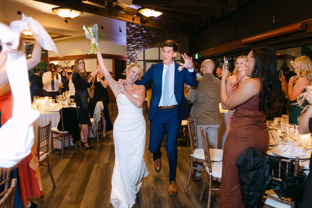Wedding guests enjoying themselves on a rustic wooden dance floor at an indoor reception venue.