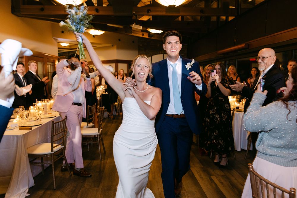 Wedding guests dance and celebrate together on a dimly lit dance floor during an evening reception.
