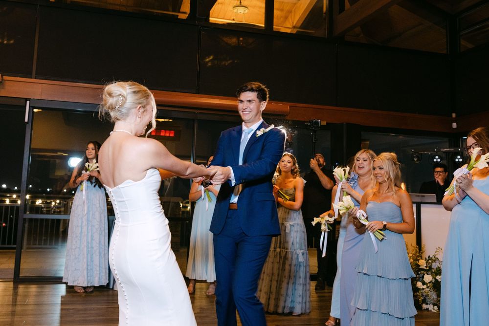 Couple shares a joyful dance moment at their wedding reception with guests looking on.
