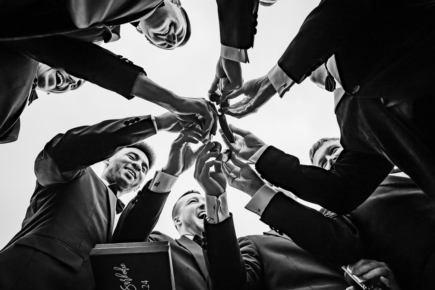 A low angle black and white shot of business people standing in a circle looking down at the camera.