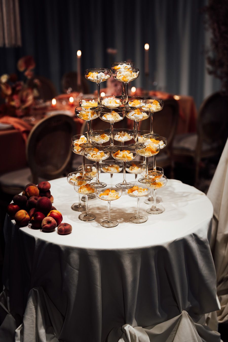 Elegant candle centerpiece display on round table with white tablecloth and black overlay for formal dining event.