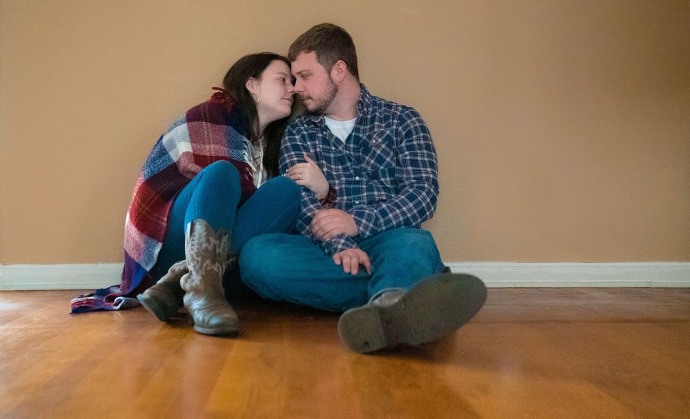 A couple in plaid shirts sits together on a hardwood floor in a romantic photo sequence.