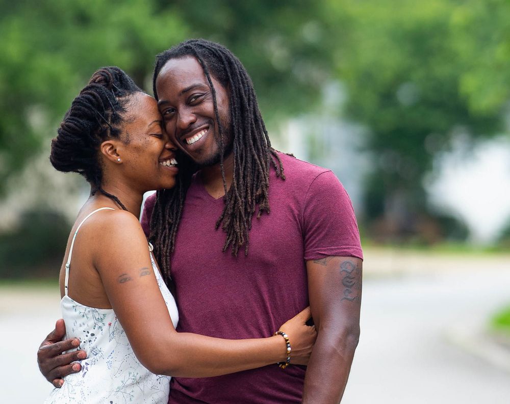 A couple shares a romantic moment together outdoors while wearing coordinating burgundy and white outfits.