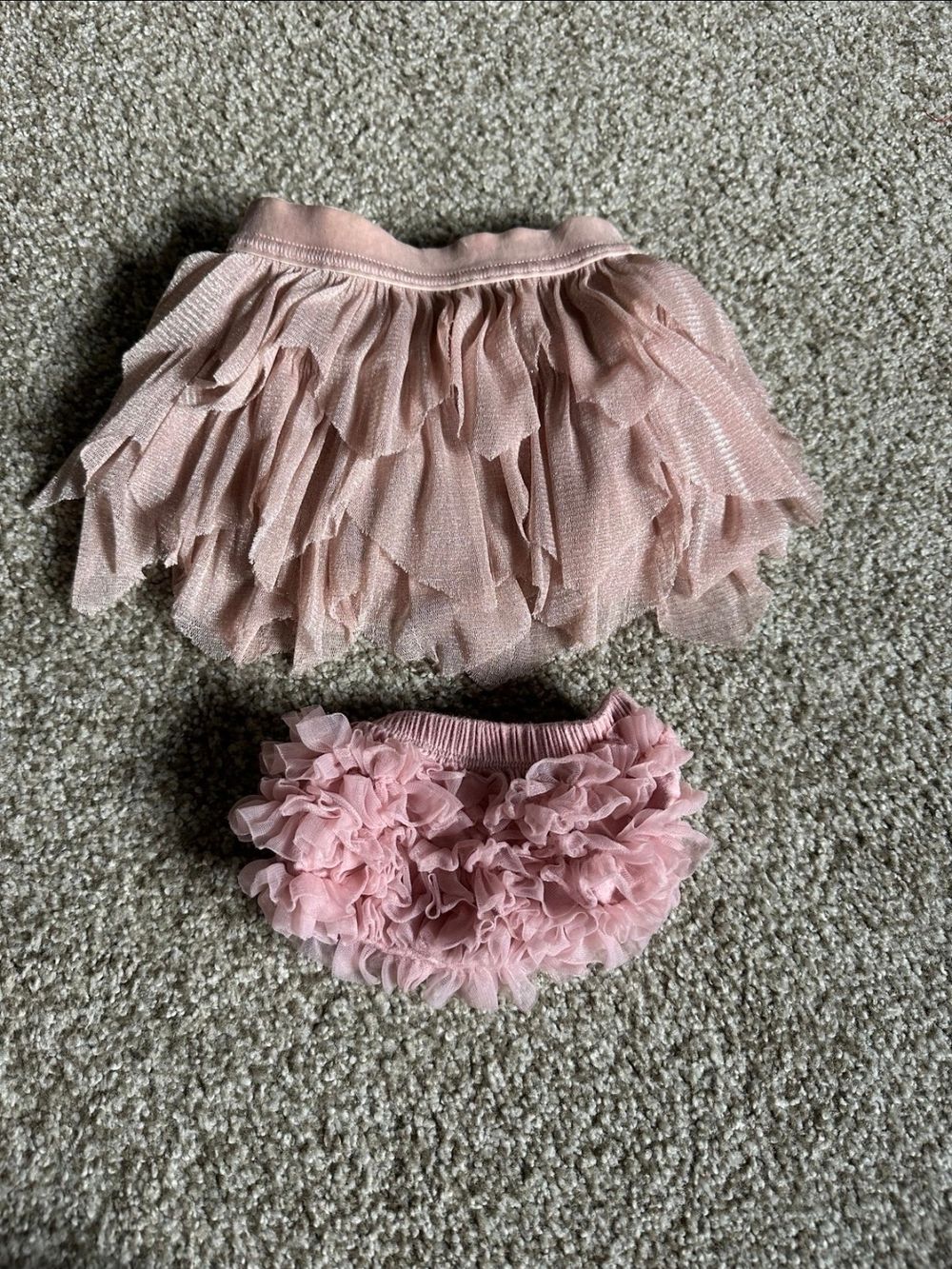 Pink tulle baby tutu skirt with delicate ruffles and floral embellishments shown in six different angles on gray carpet.
