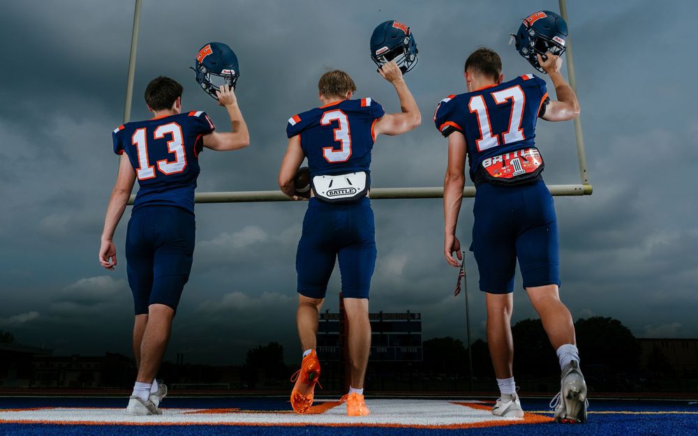 Hershey Trojans football players Media Day group portrait holding helmets at goal post, by Deanna Fox, SportsFox Photography, Hershey PA