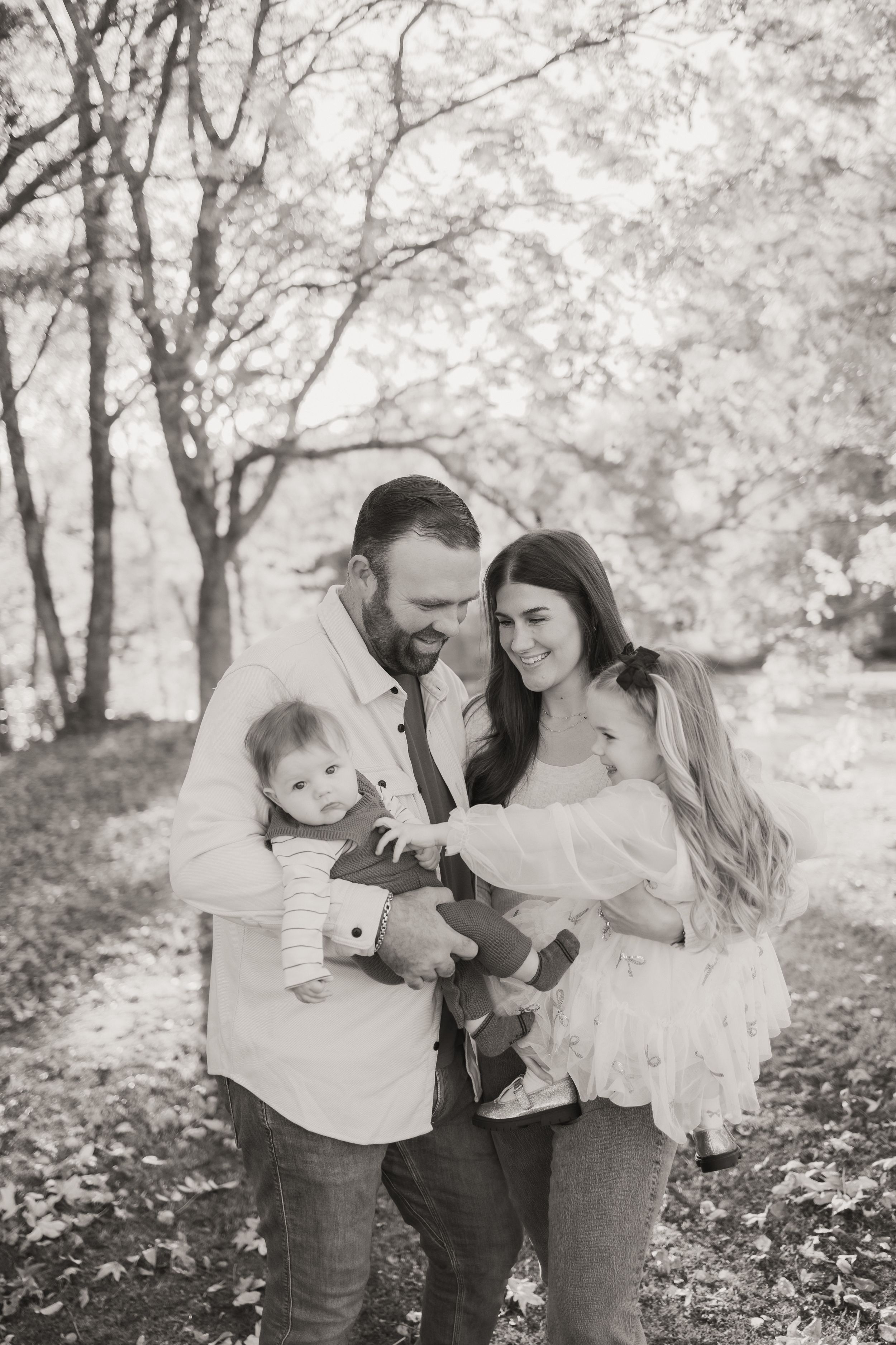 A family shares intimate moments together in a dreamy outdoor setting with autumn leaves and soft lighting.