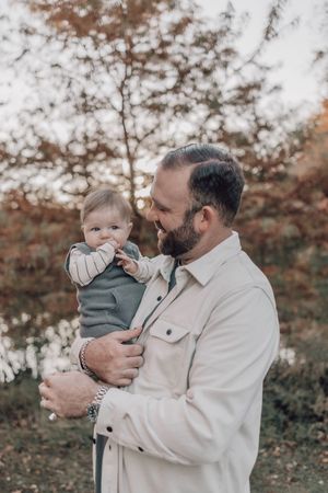 Candid family portraits showing tender moments between parent and child against a natural autumn backdrop.
