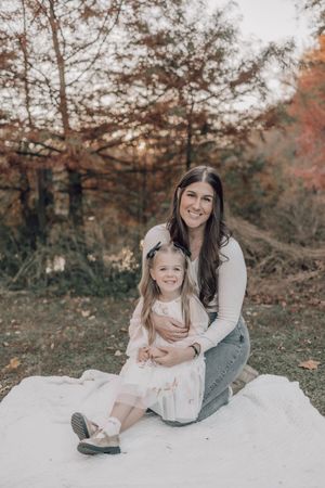 A sweet family portrait on a white blanket with autumn foliage creating a beautiful natural backdrop.