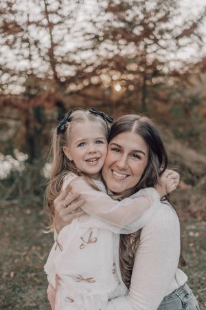 A joyful embrace between parent and child amidst autumn foliage with warm golden lighting.
