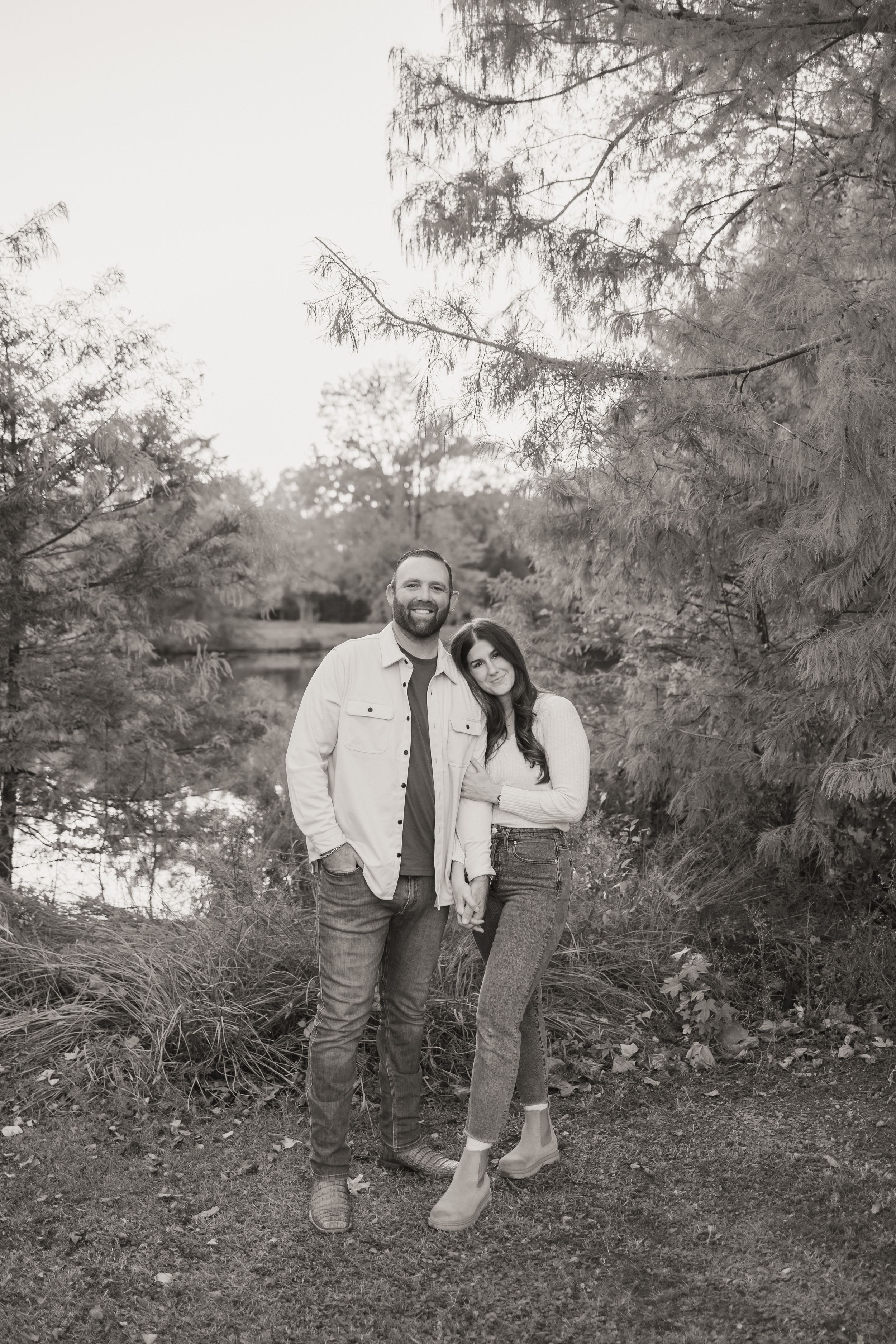 Black and white family portrait captured in a natural outdoor setting with trees in background.
