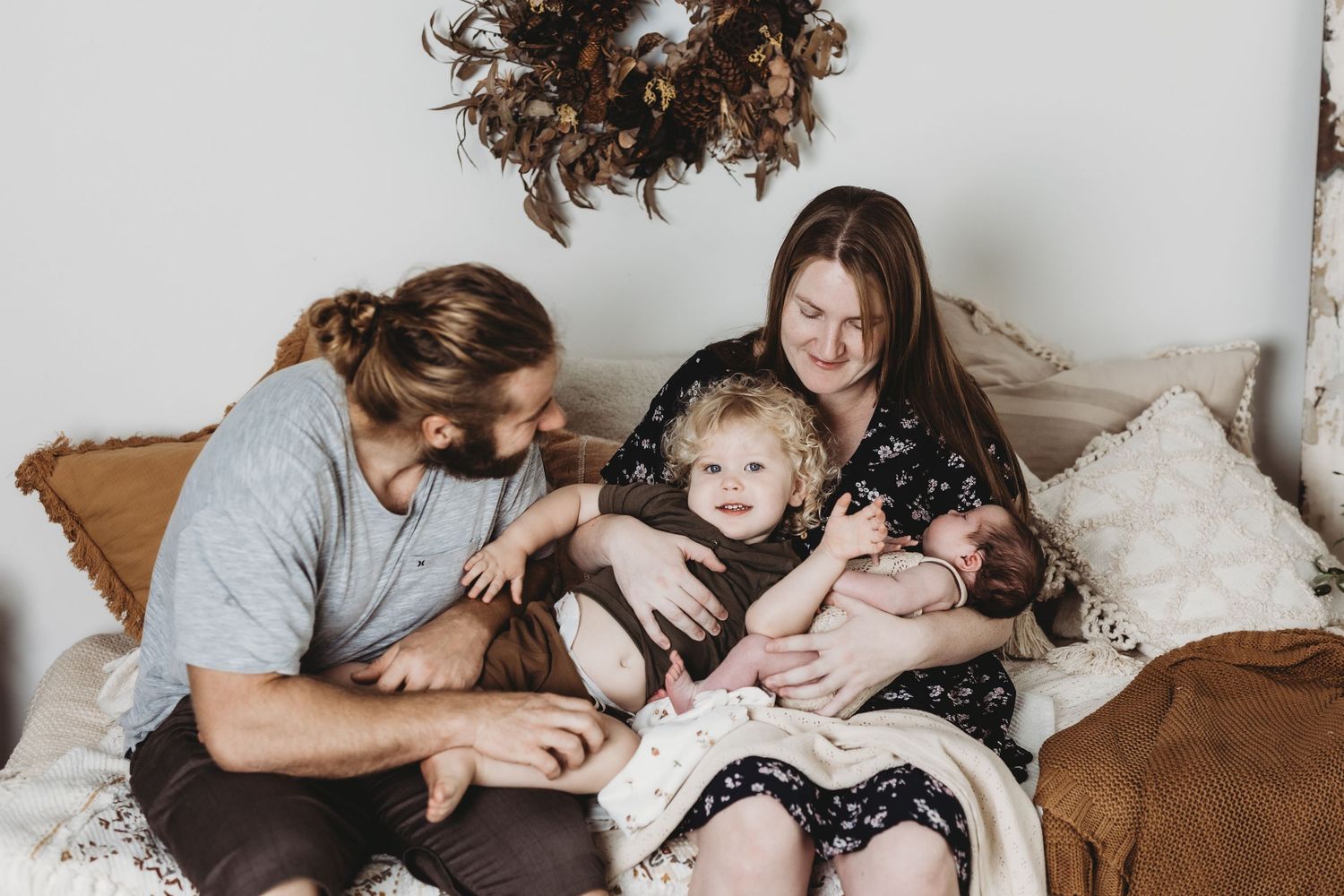 Family cuddling together on brown couch during lifestyle photoshoot.